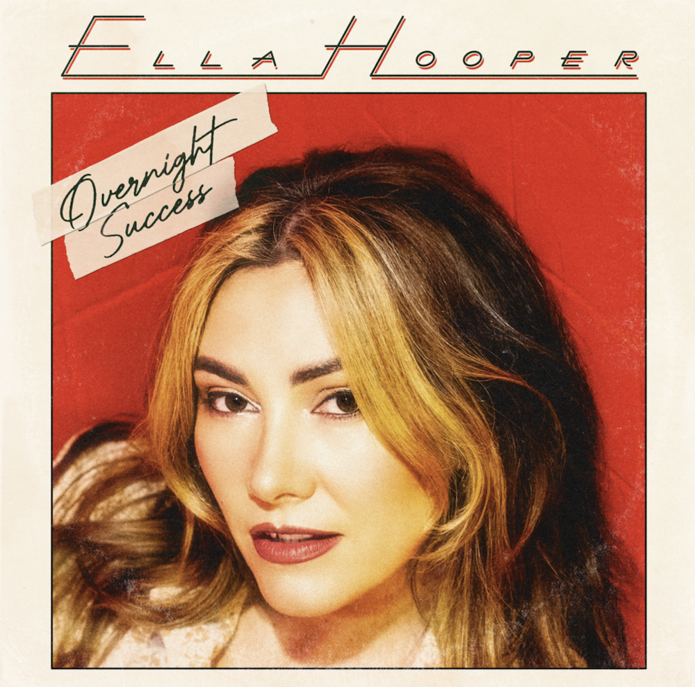Album cover art for Ella Hooper’s single Overnight Success featuring a close-up portrait of the singer against a red backdrop with retro text.